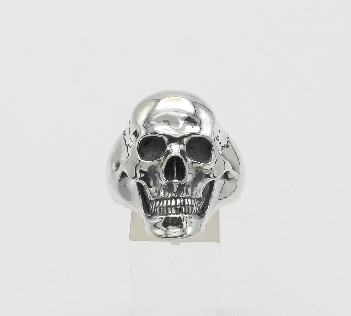 Silver skull-shaped ring on a white background