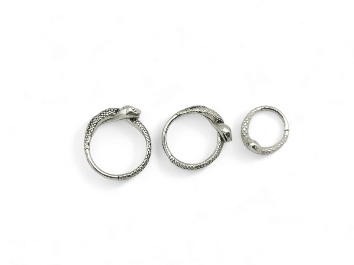 Three surgical steel serpent clicker rings on a white background