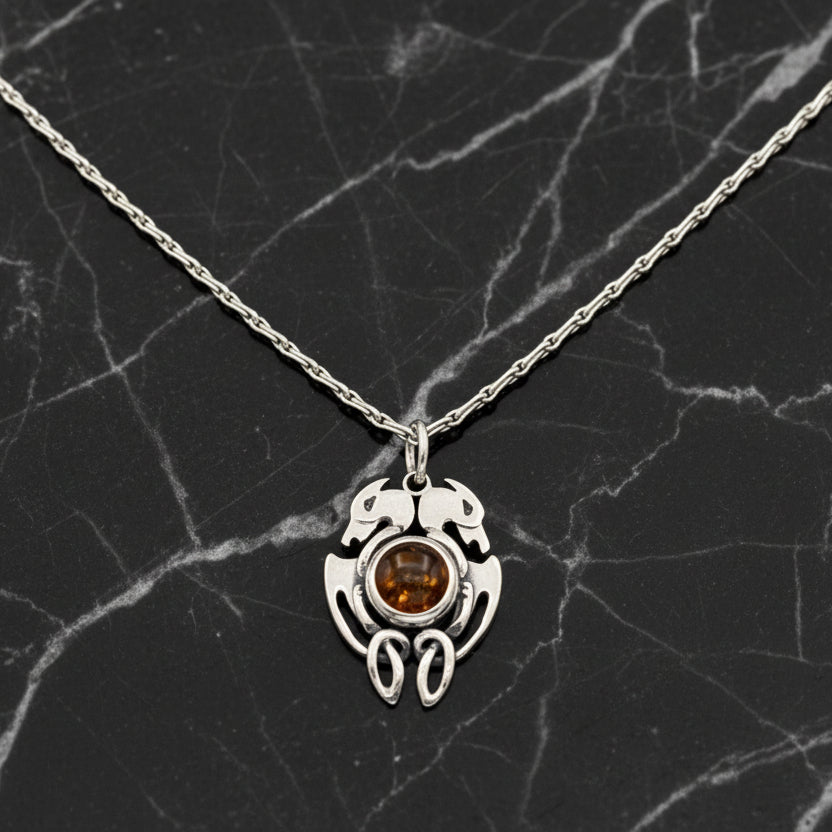 Silver necklace with a pendant featuring a orange gemstone on a black background