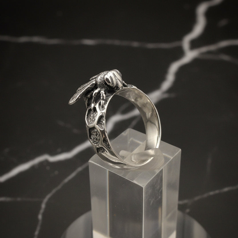 Silver ring with a unique design on a clear stand against a dark background