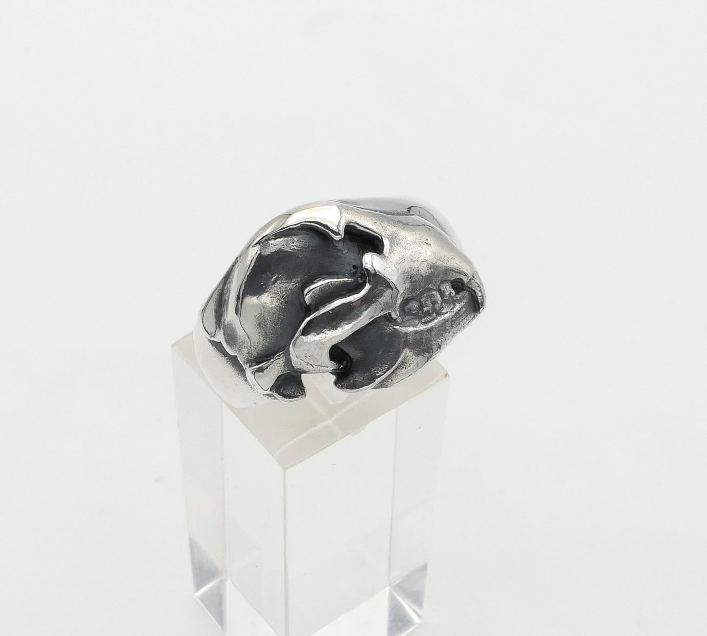 Silver bear skull ring on a clear stand against a white background