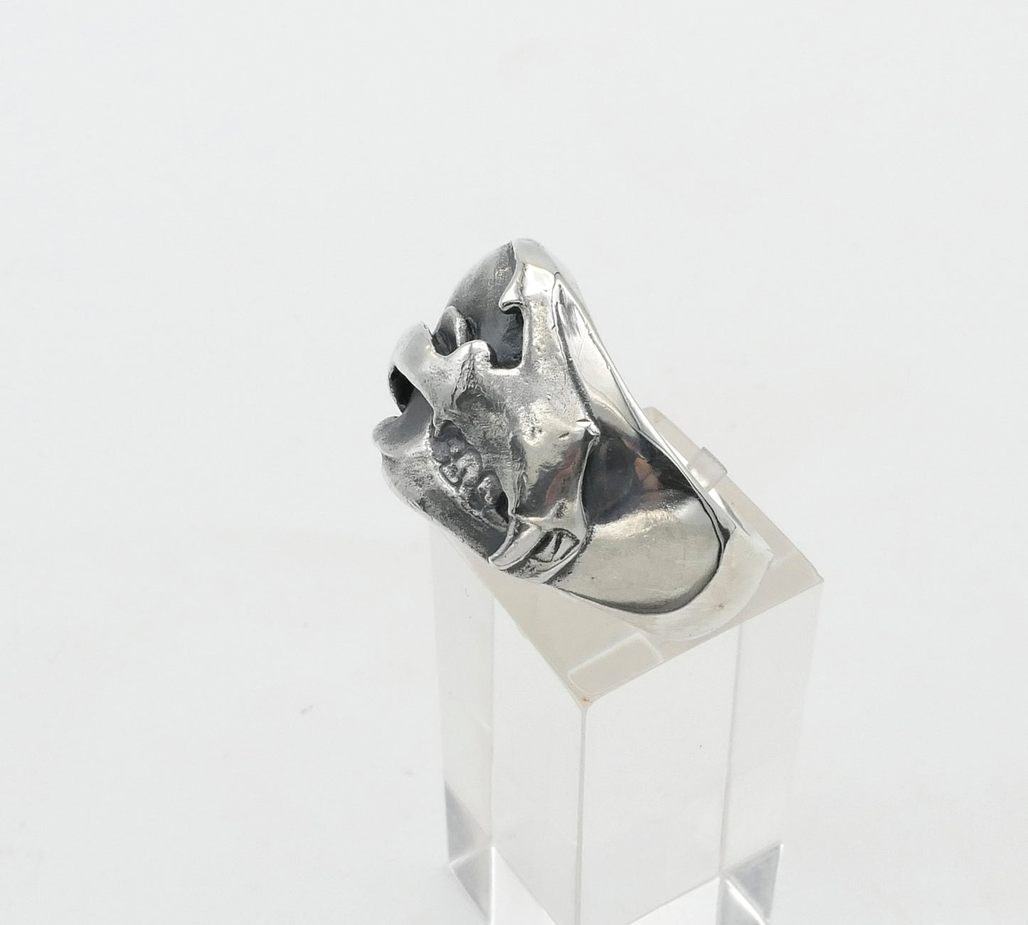 Silver bear skull ring with a unique design on a clear stand against a white background