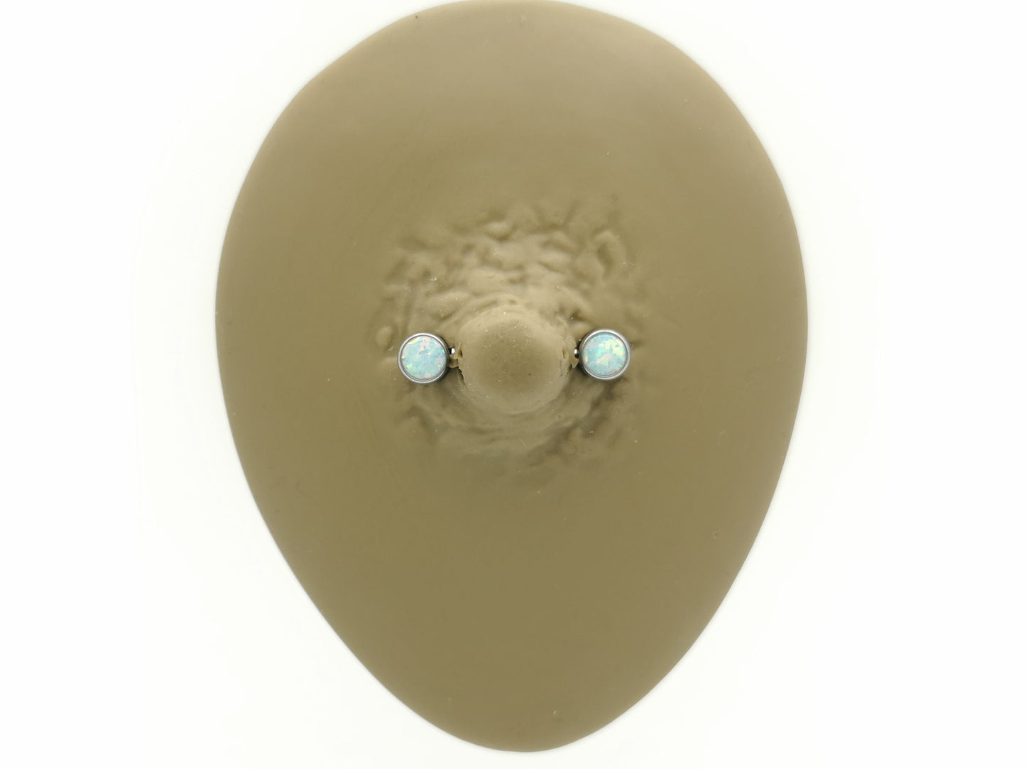 A disc-shaped titanium nipple bars with bezel settings and white opal jewels.