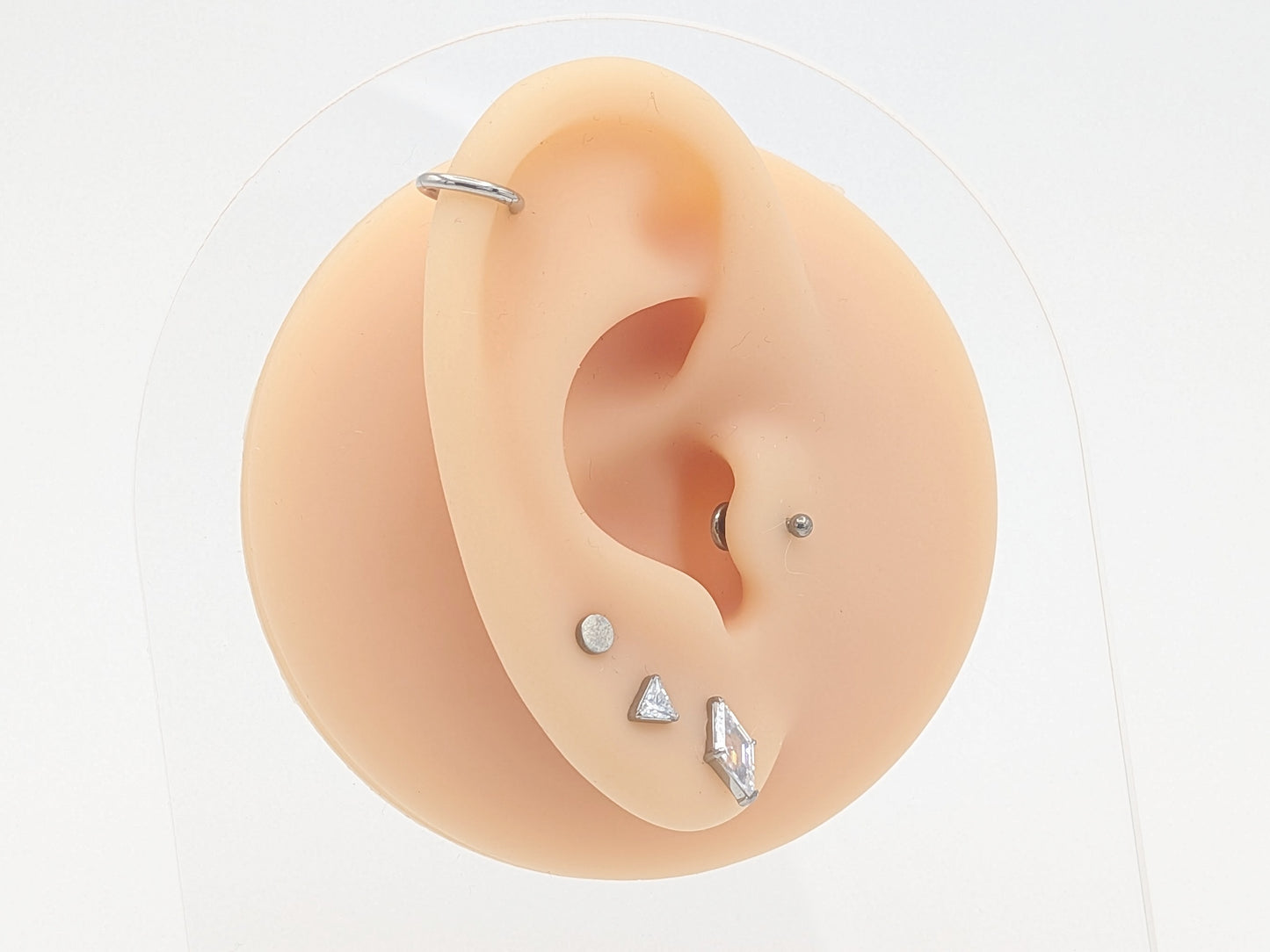 Ear with various earrings on a white background