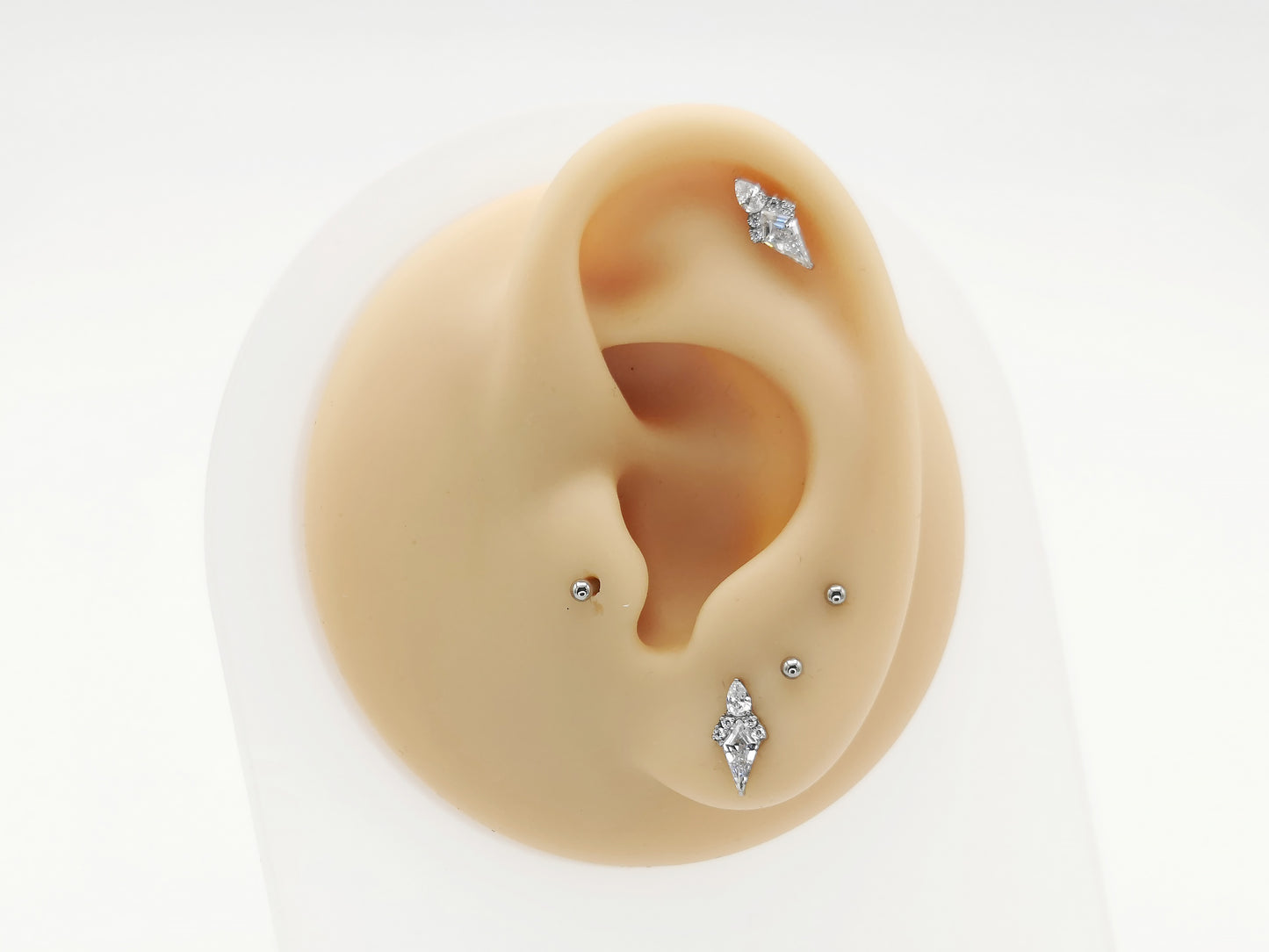Titanium claw set kite studs on a mannequin ear