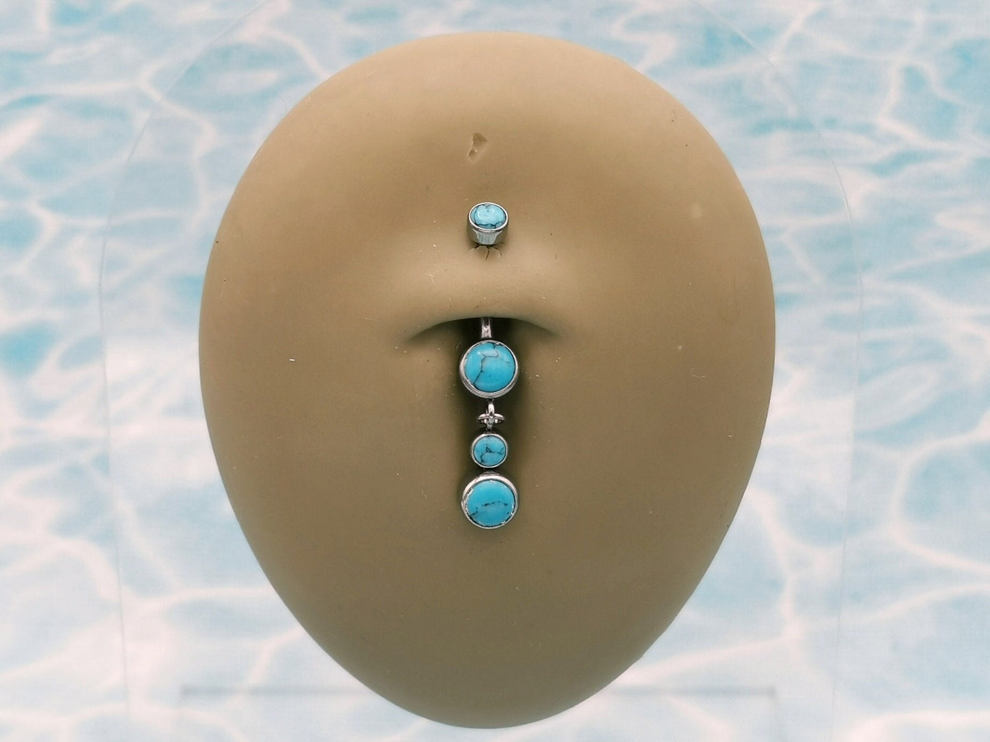 A titanium belly bar jewellery with blue turquoise gemstones and silver-colored ends.