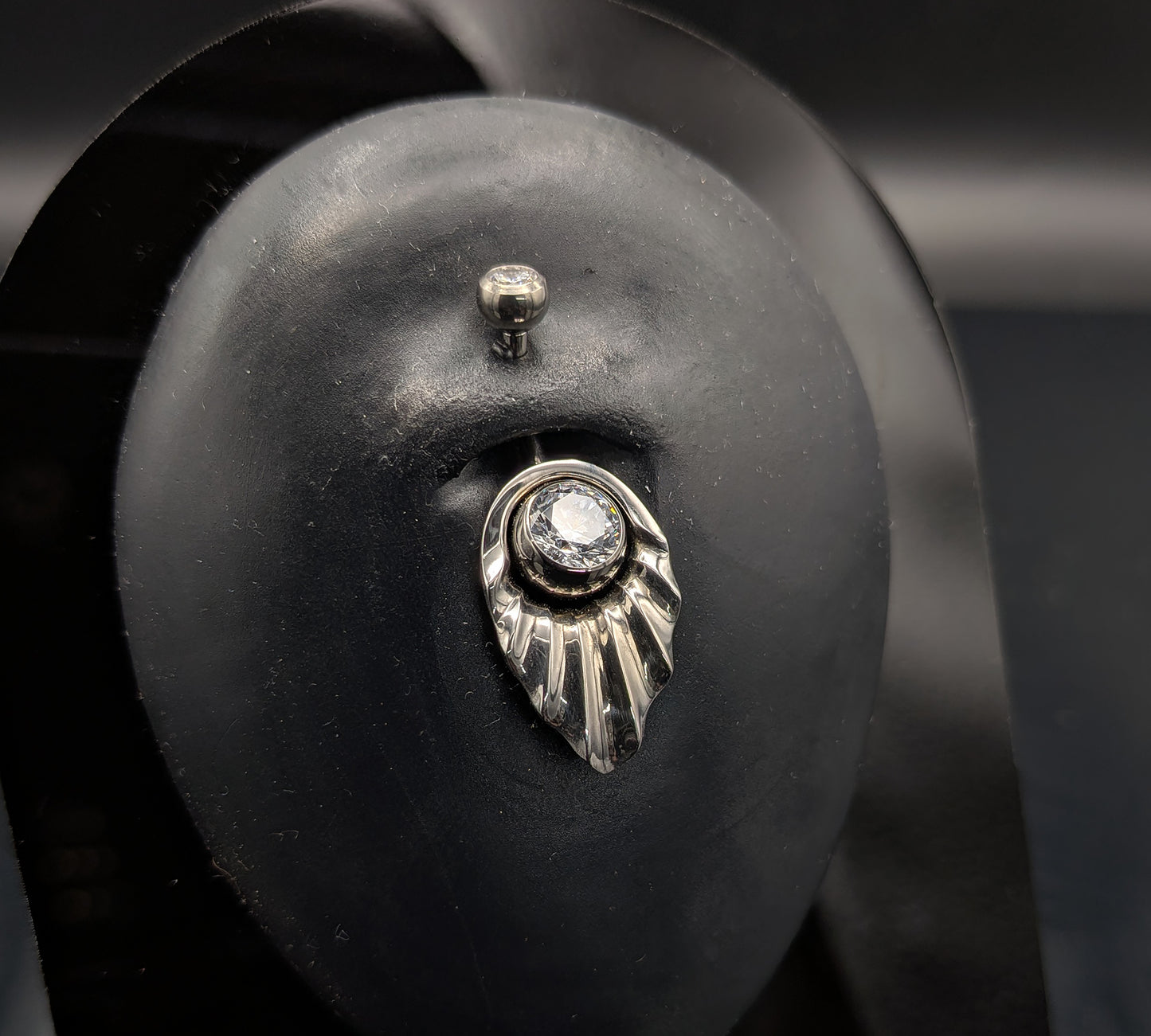 Art Deco style navel shield with a crystal jewelled navel bar on a dark background