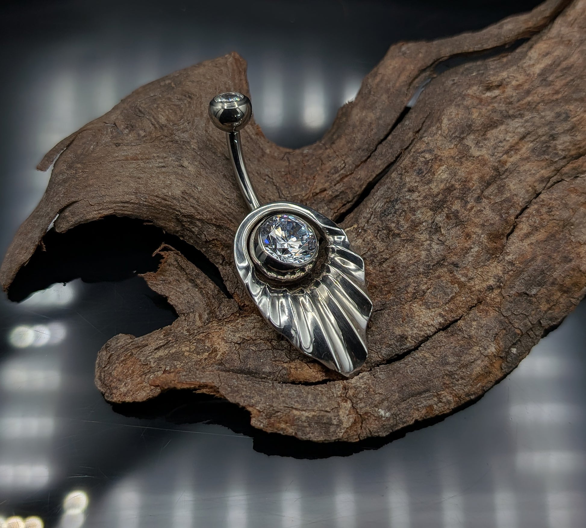 Art Deco style navel shield with a crystal jewelled navel bar on a dark background