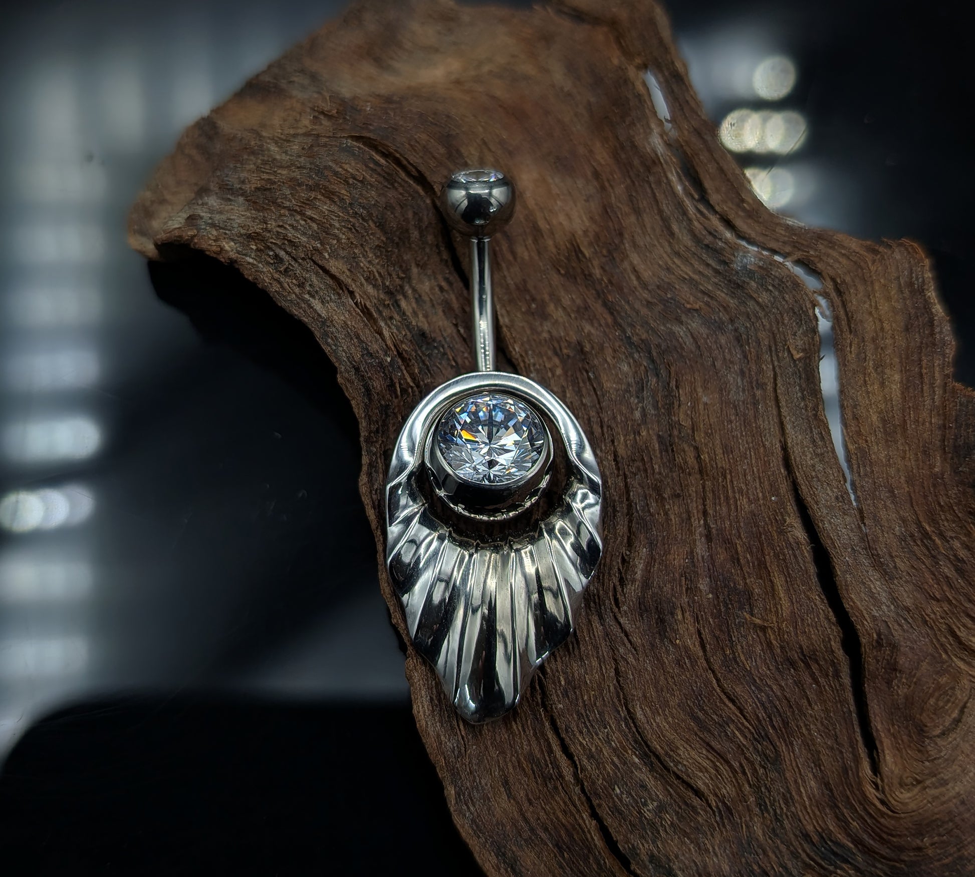 Art Deco style navel shield with a crystal jewelled navel bar on a dark background