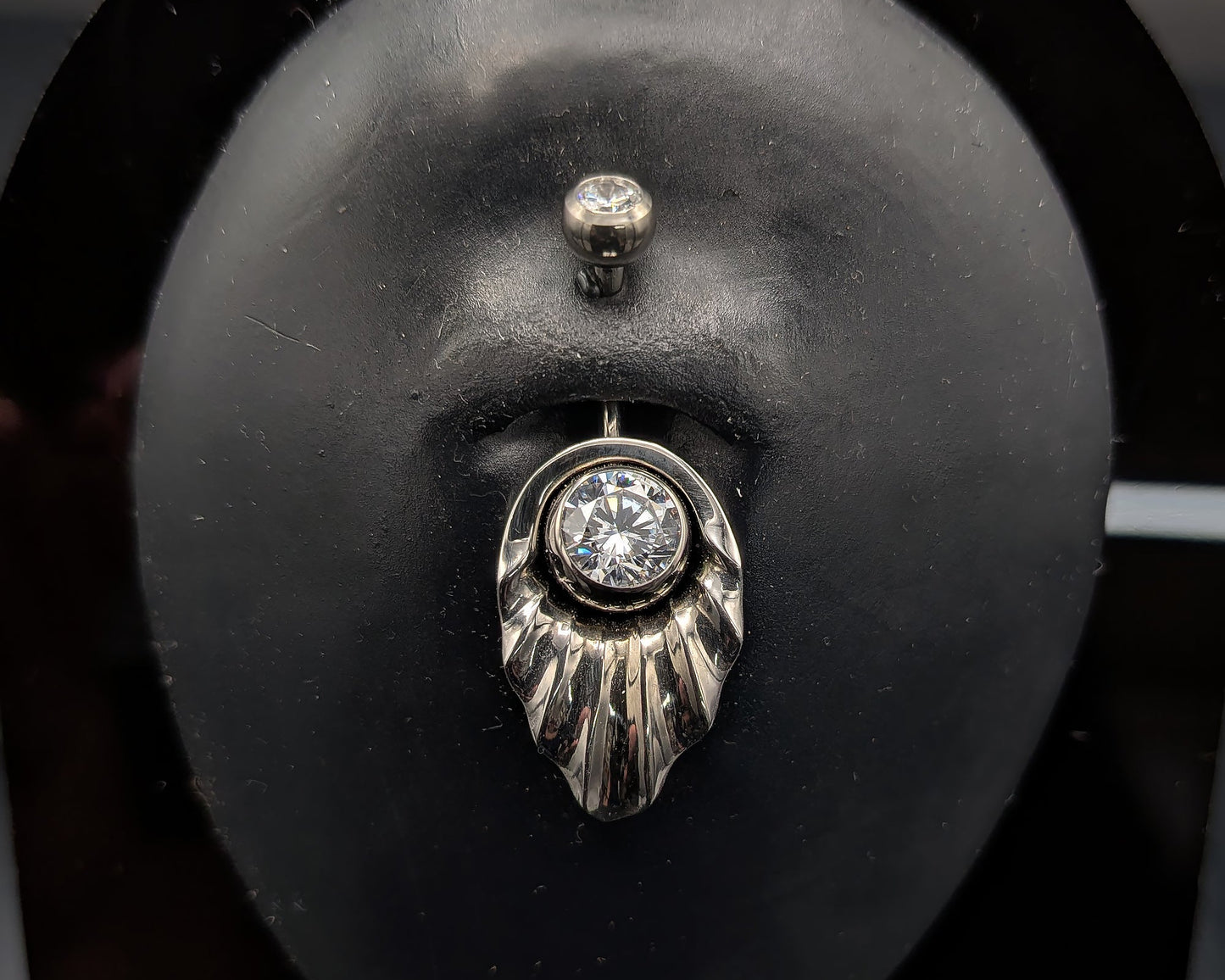 Art Deco style navel shield with a crystal jewelled navel bar on a dark background