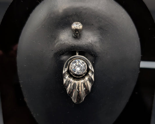 Art Deco style navel shield with a crystal jewelled navel bar on a dark background