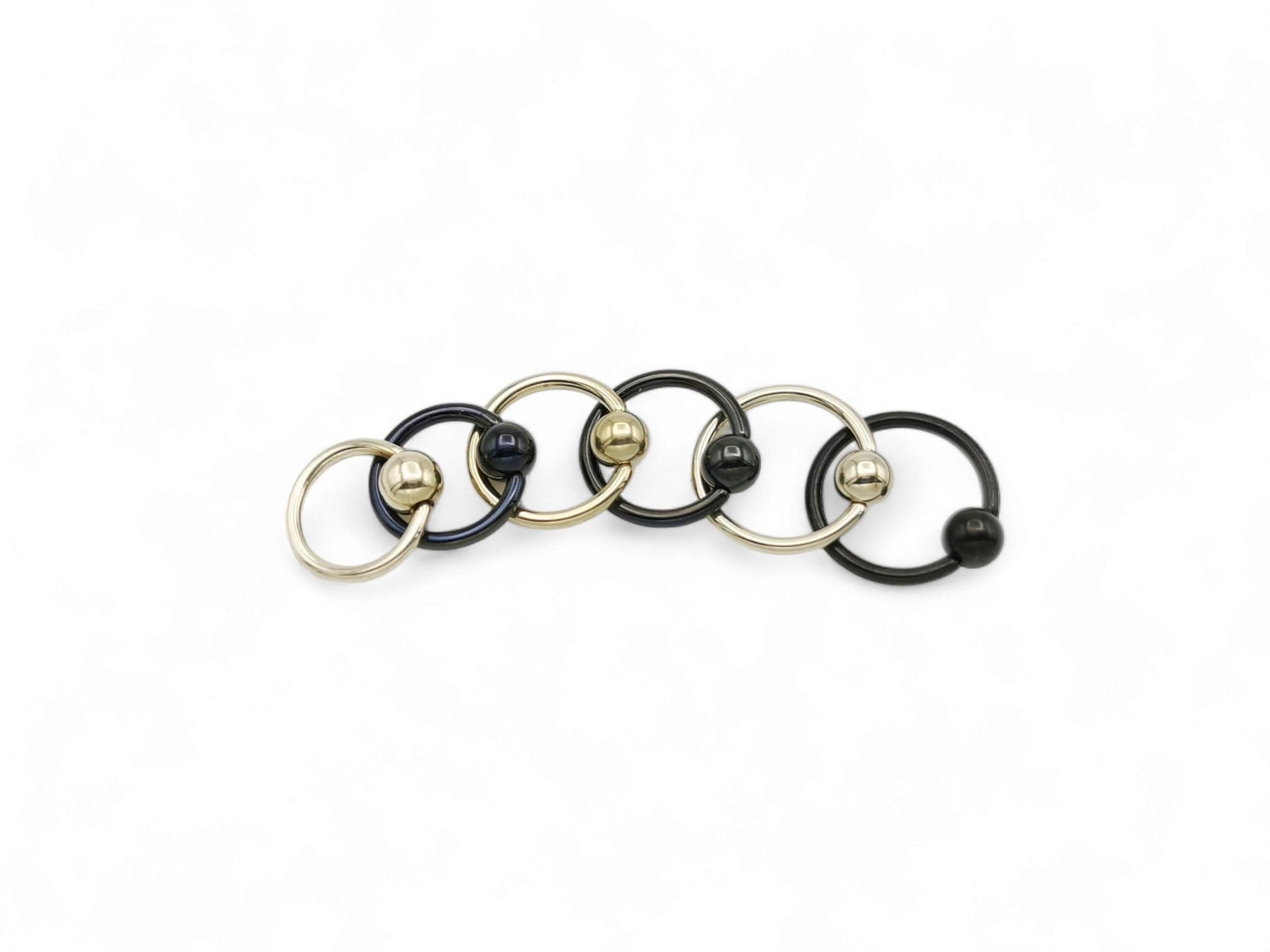 A collection of black and gold titanium BCRs with a 4mm ball closure design, displayed against a white background.