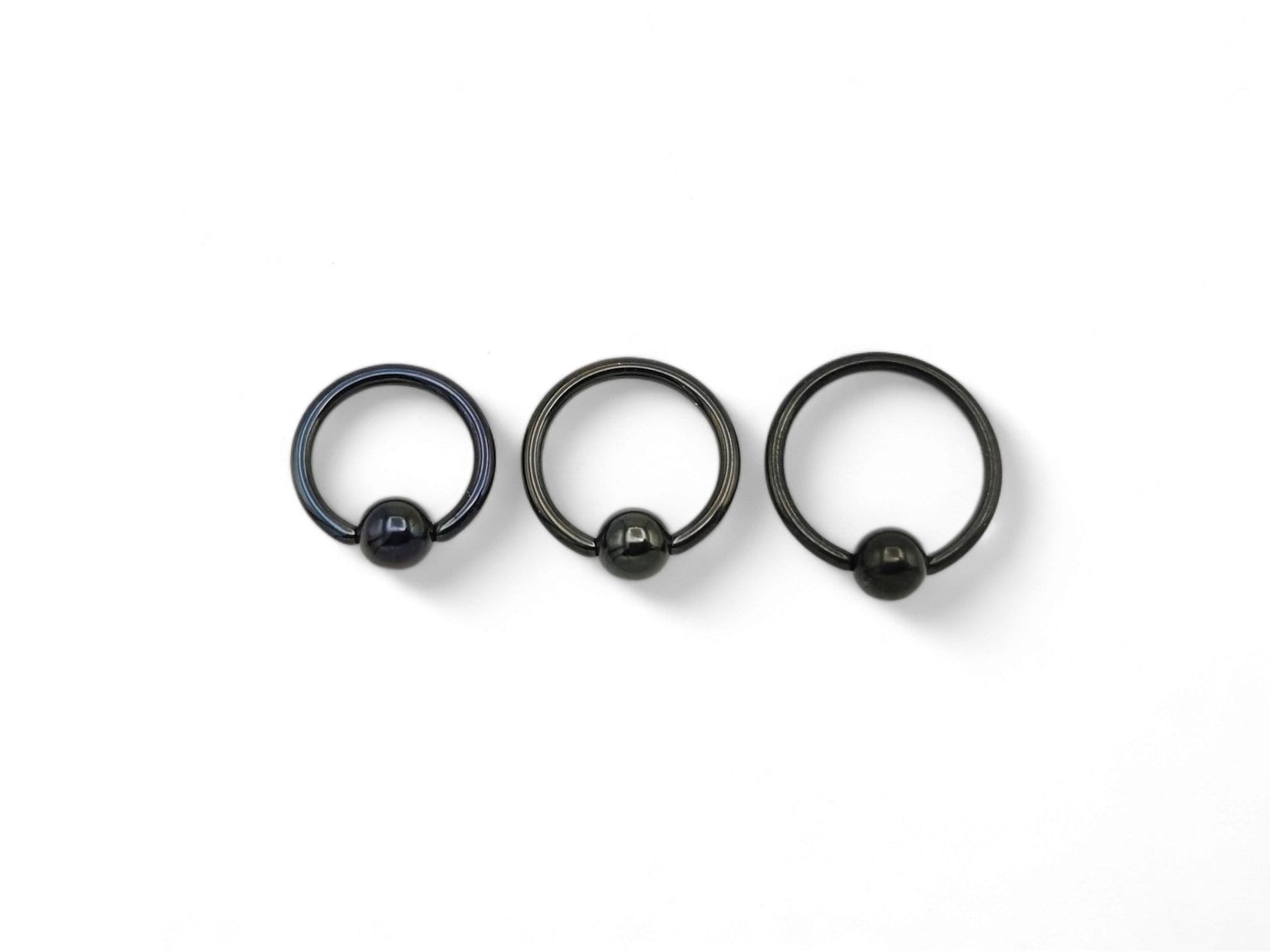 A collection of black titanium BCRs with a 4mm ball closure design, displayed against a white background.