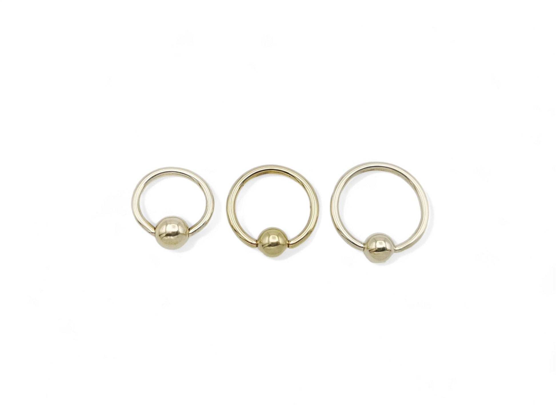 A collection of gold titanium BCRs with a 4mm ball closure design, displayed against a white background.