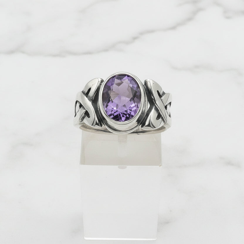 Silver ring with a purple gemstone on a white background