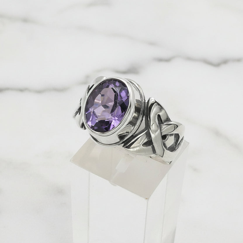 Silver ring with a purple gemstone on a white background