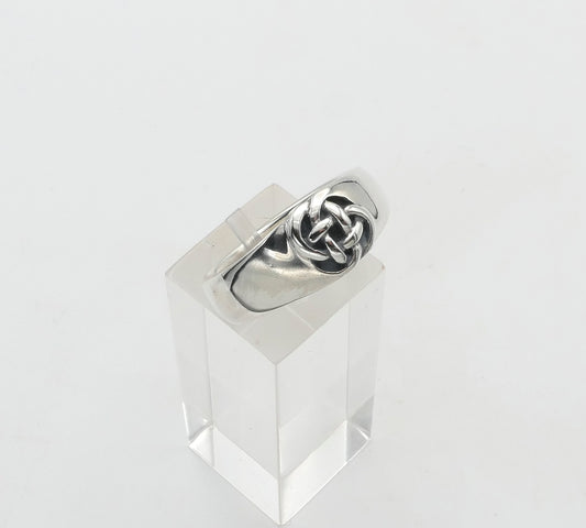 Silver ring with a knot design on a clear stand against a white background
