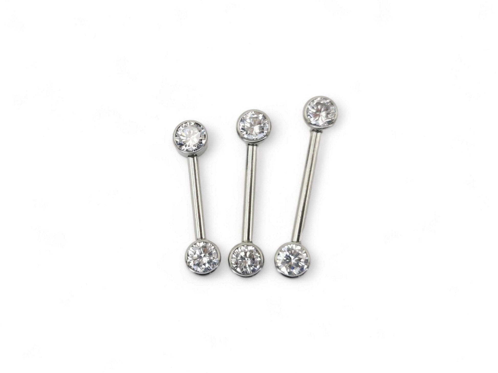 A set of three jewelled titanium barbells with clear faceted crystals, arranged in a row on a white background.