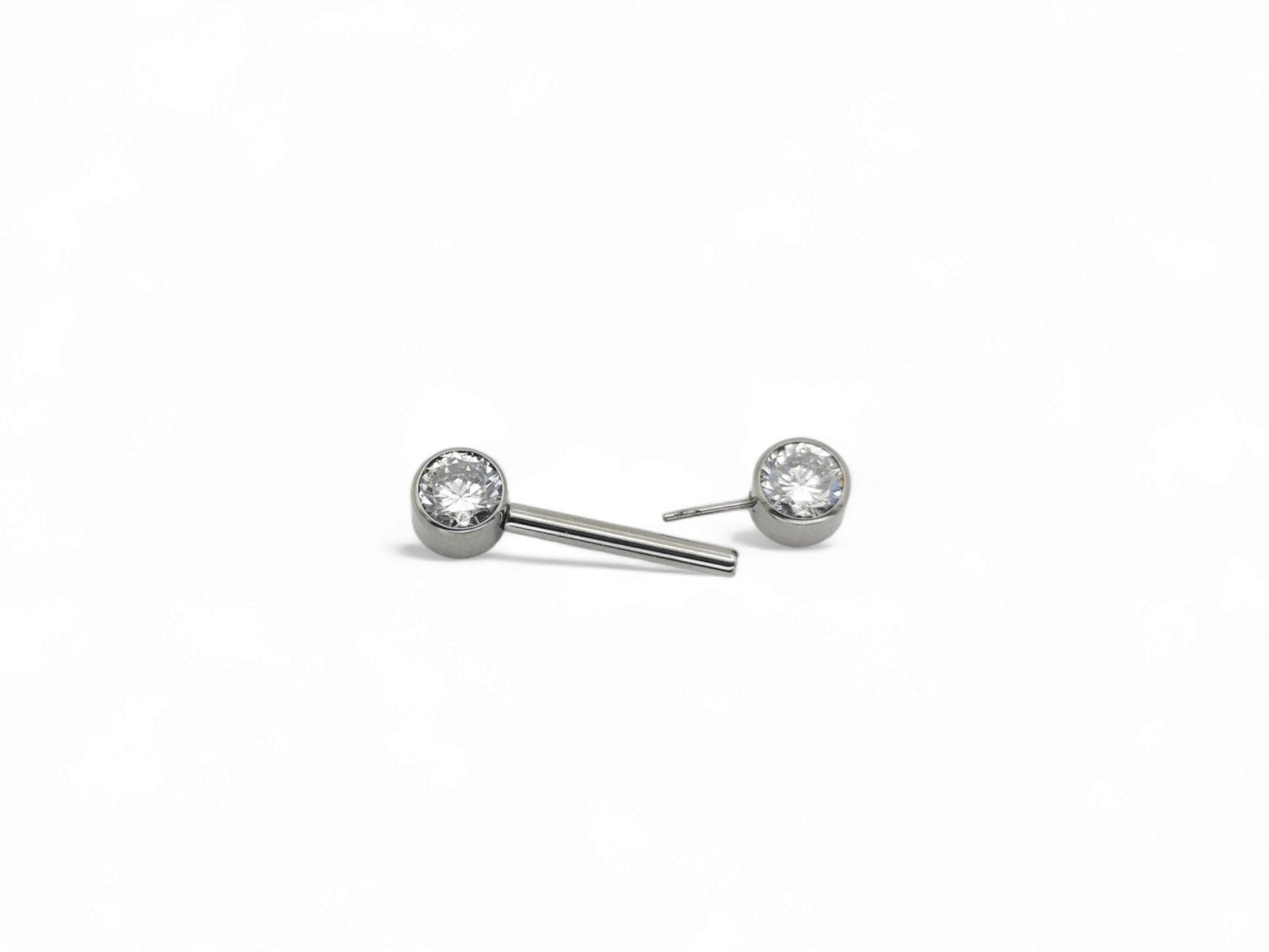 A set of three jewelled titanium barbells with clear faceted crystals, arranged in a row on a white background.