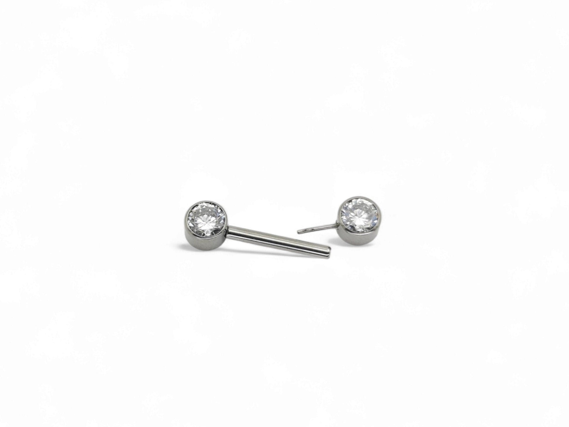 A set of three jewelled titanium barbells with clear faceted crystals, arranged in a row on a white background.
