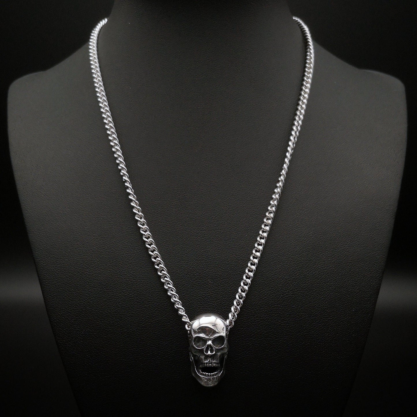 Silver skull necklace on a black mannequin with a dark background