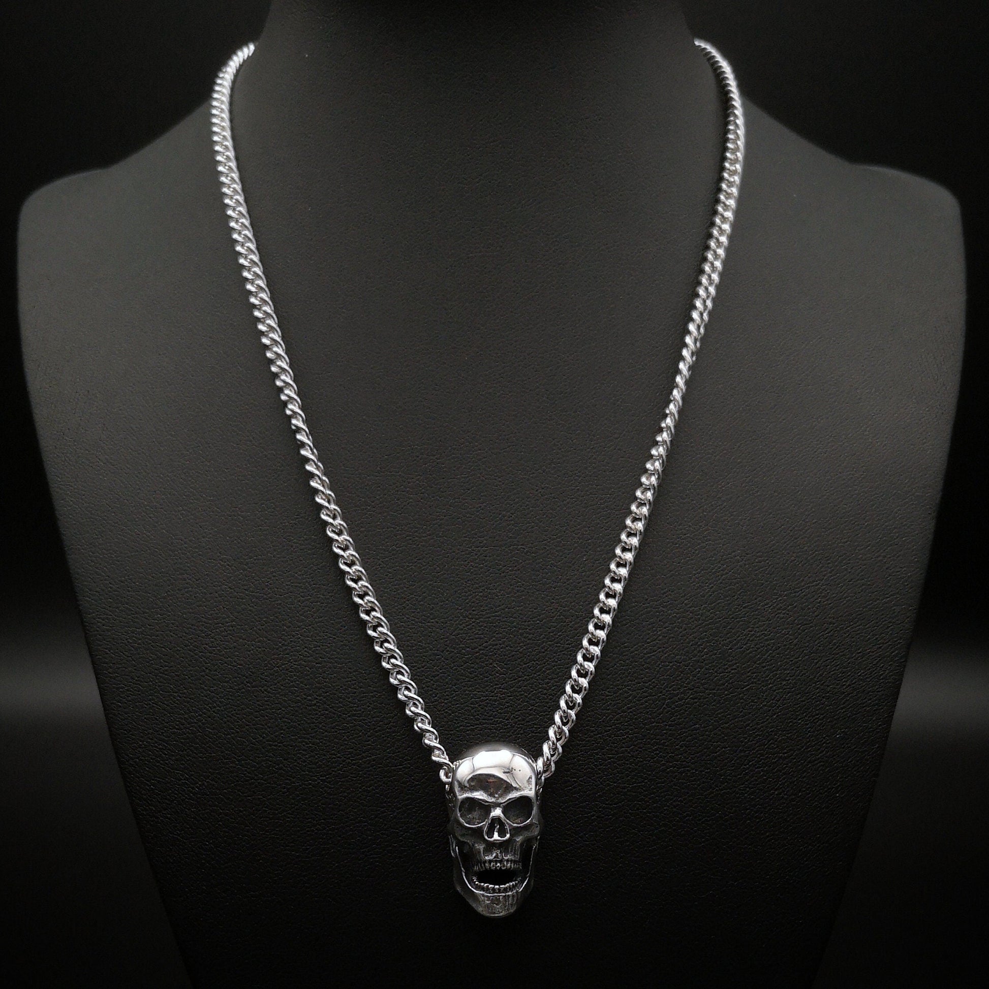 Silver skull necklace on a black mannequin with a dark background