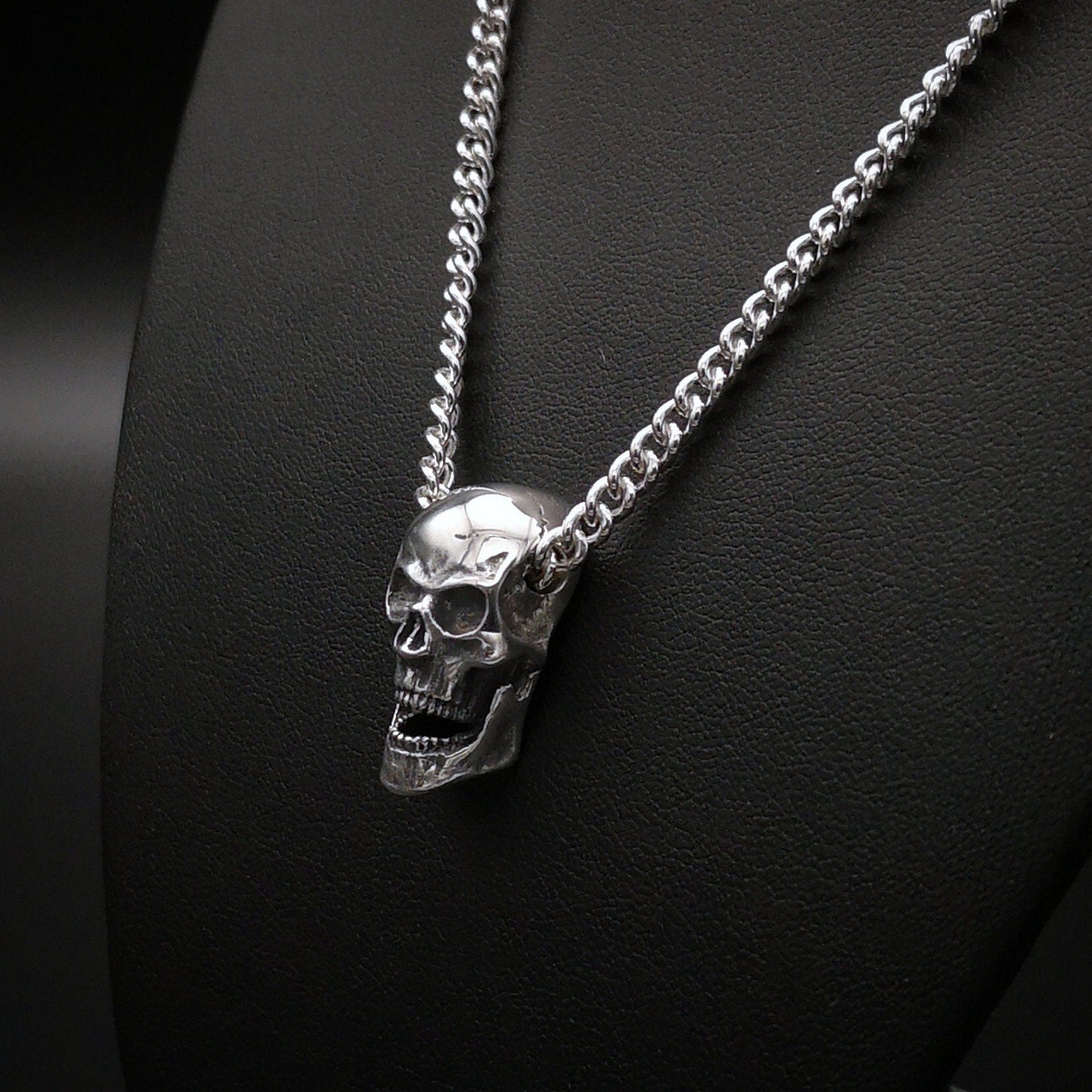 Silver skull pendant necklace on a black background