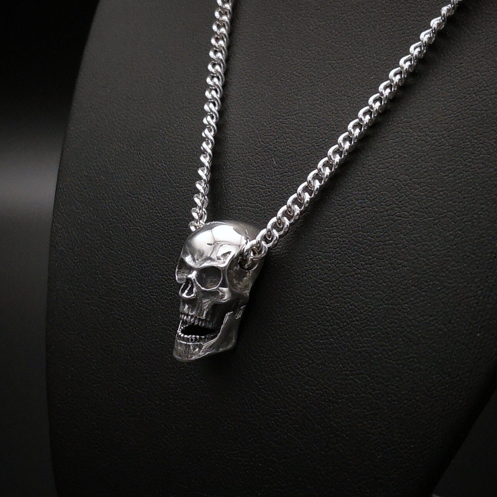 Silver skull pendant necklace on a black background
