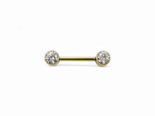 A gold-colored titanium barbell with a clear faceted crystal on the bezel, intended for nipple piercings.