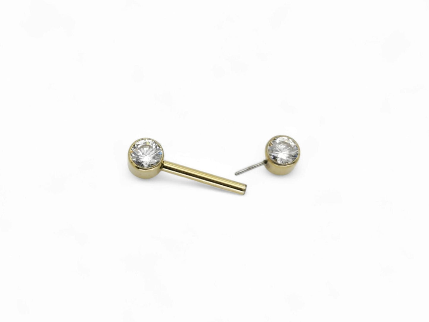 A gold-colored titanium barbell with a clear faceted crystal on the bezel, intended for nipple piercings.
