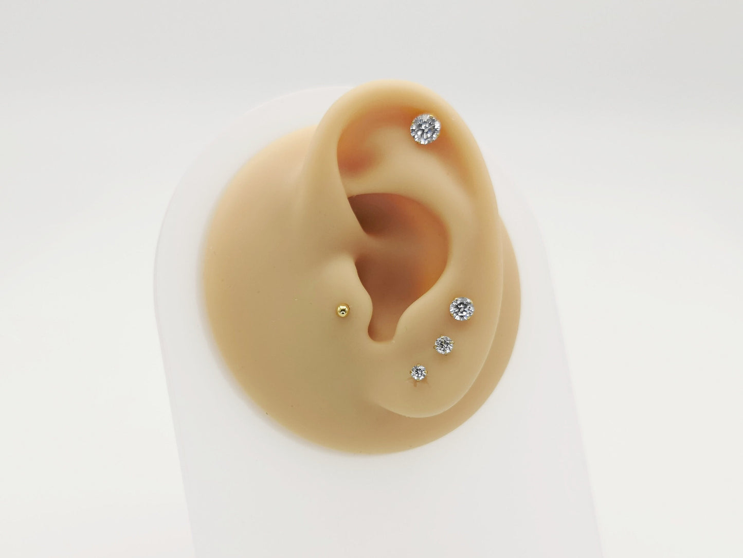 Set of gold stud earrings with clear gemstones on a white background