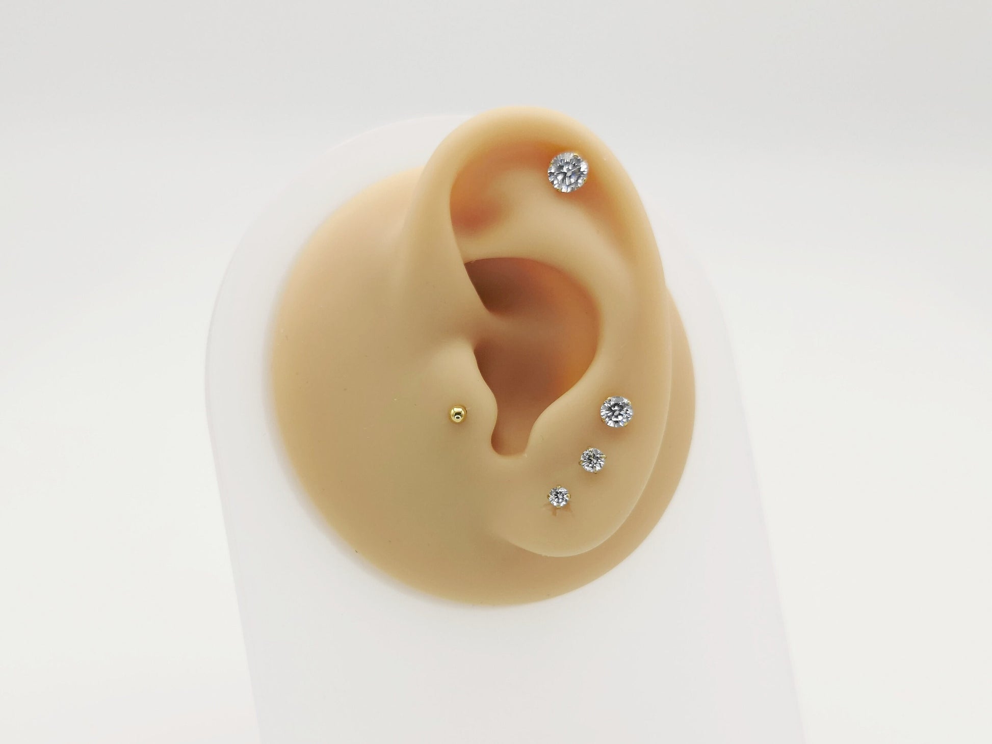Set of gold stud earrings with clear gemstones on a white background
