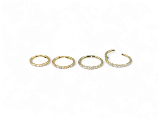 Gold titanium jewelled clicker rings on a white background