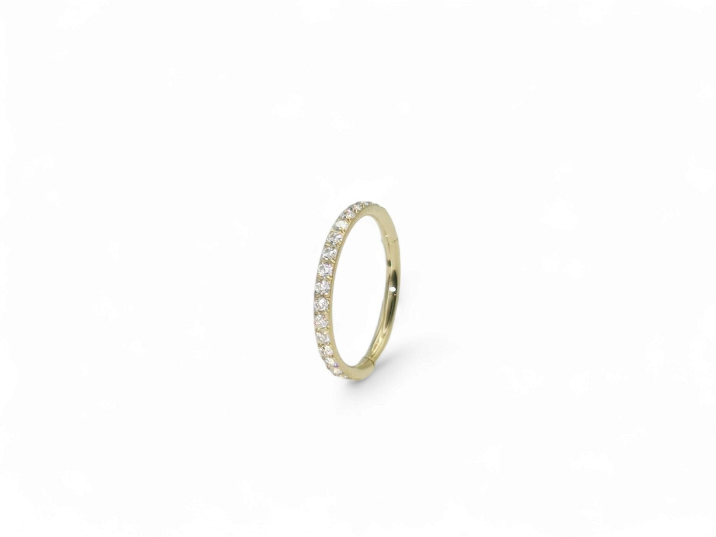 A gold titanium jewelled clicker ring with a zircon gold finish, featuring a pave set of clear crystal gemstones.