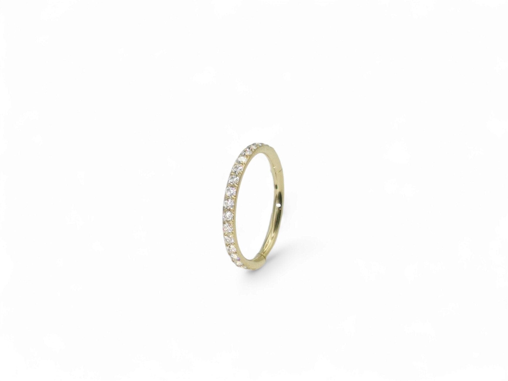 A gold titanium jewelled clicker ring with a zircon gold finish, featuring a pave set of clear crystal gemstones.