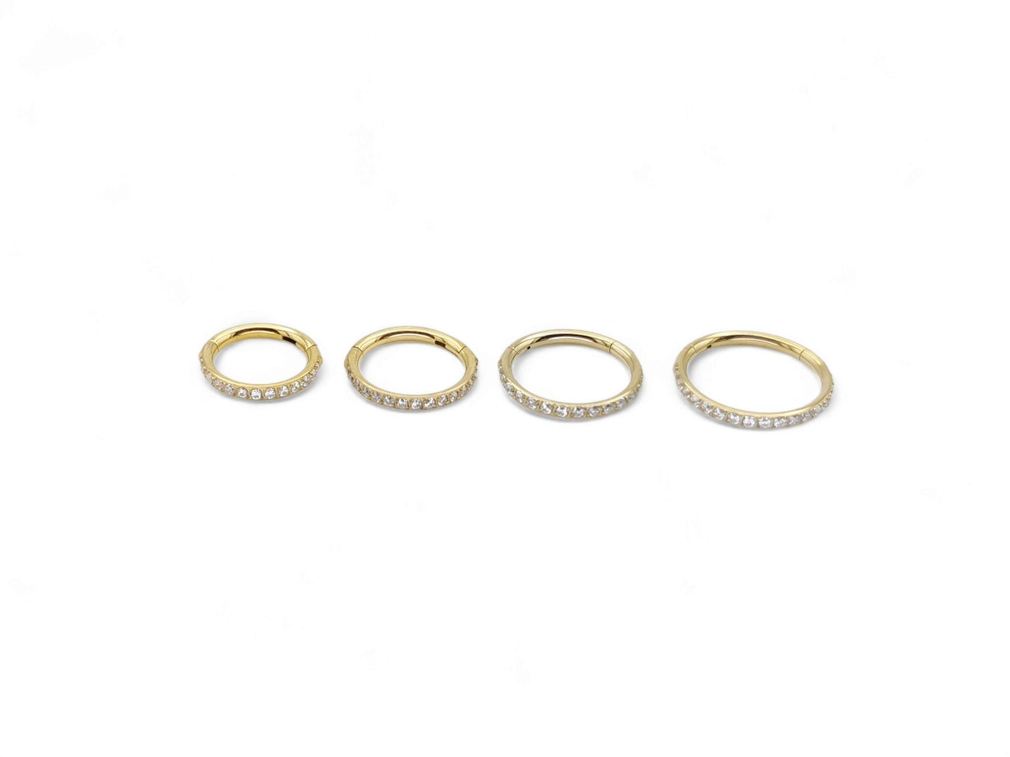 Gold titanium jewelled clicker rings on a white background