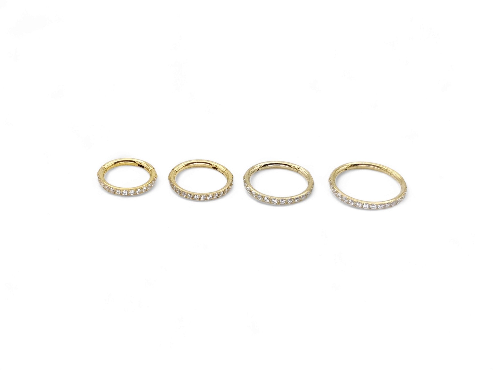 Gold titanium jewelled clicker rings on a white background