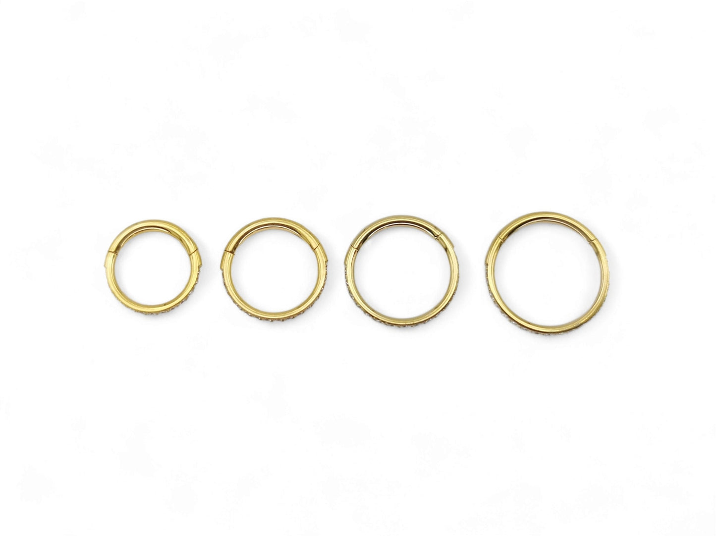 Gold titanium jewelled clicker rings on a white background