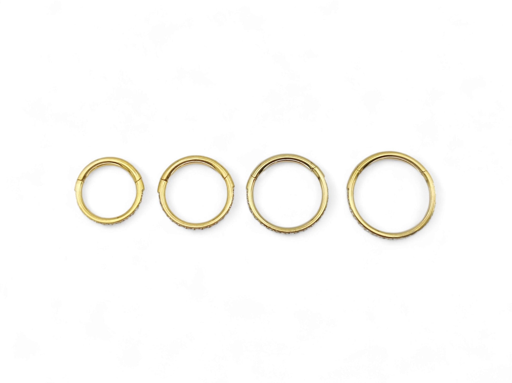 Gold titanium jewelled clicker rings on a white background