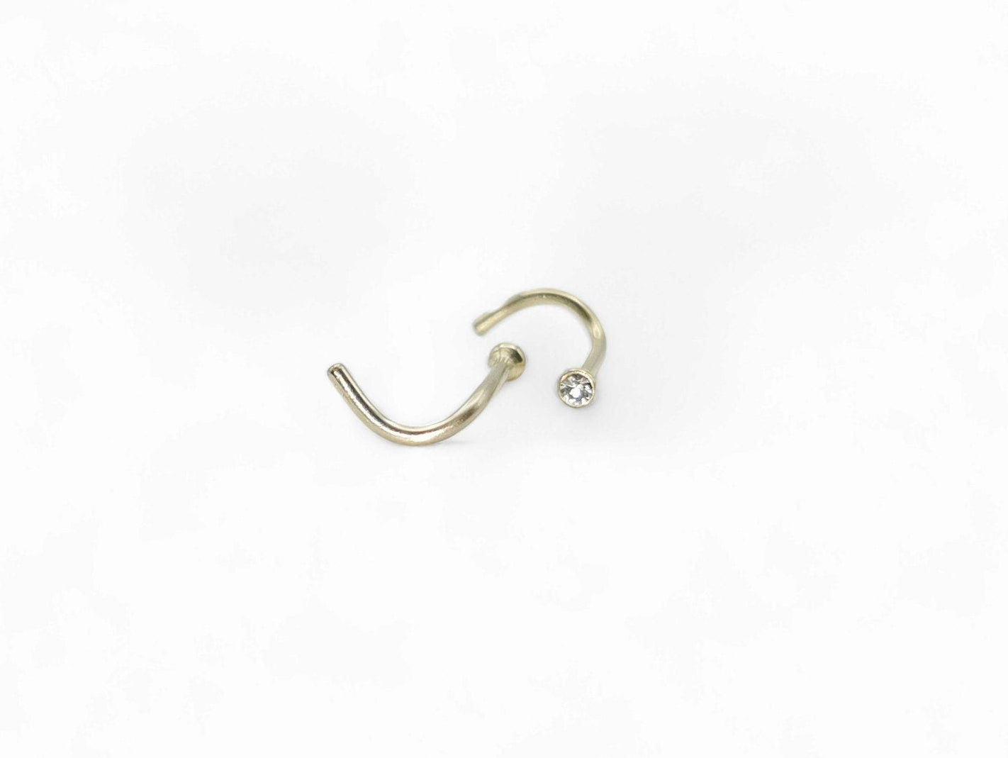 Gold titanium jewelled nose stud on a white background