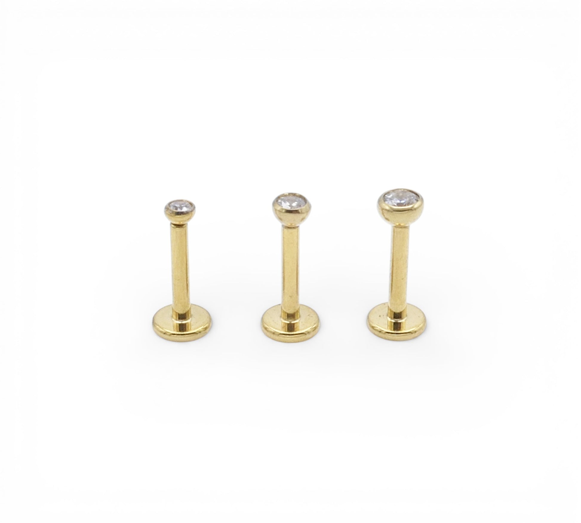 Three gold coloured studs with clear gemstones on a white background