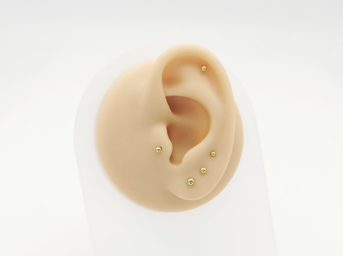 Five gold titanium studs on a white background