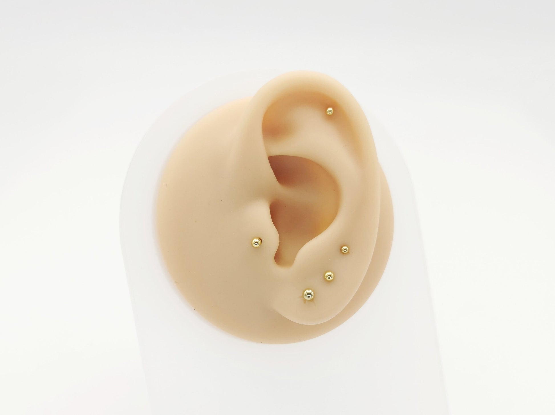 Five gold titanium studs on a white background