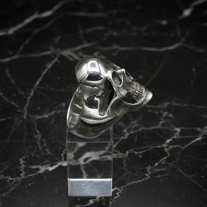 Silver skull-shaped object on a black marble surface