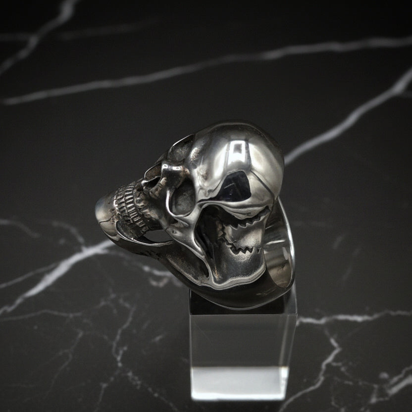 Silver skull ring on a black marble background