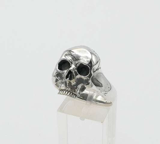 Silver skull ring on a clear stand against a white background