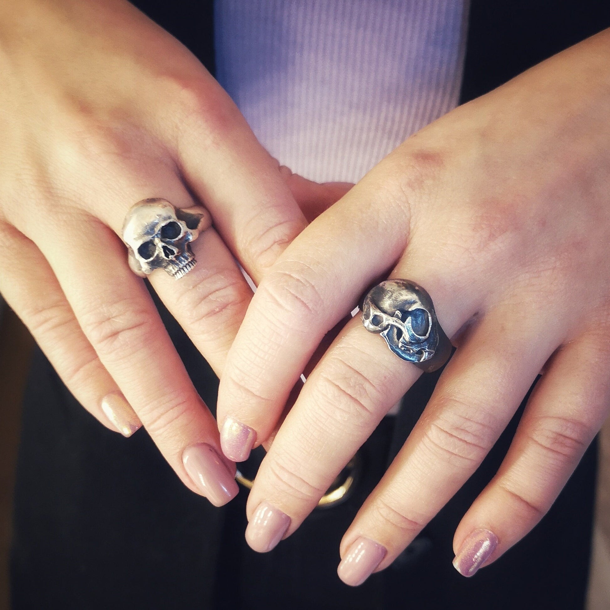 Silver skull rings on human hands
