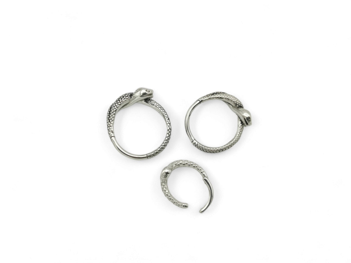 Three surgical steel serpent clicker rings on a white background