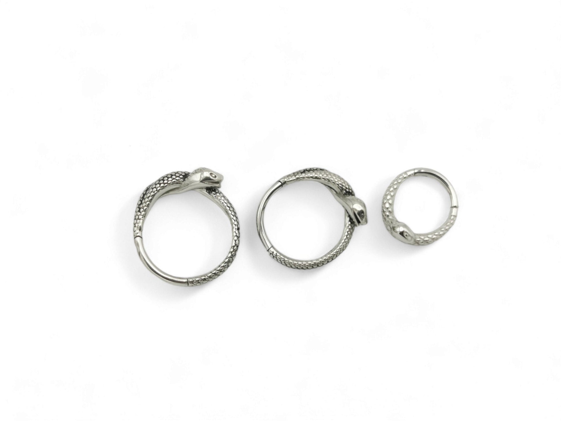Three surgical steel serpent clicker rings on a white background