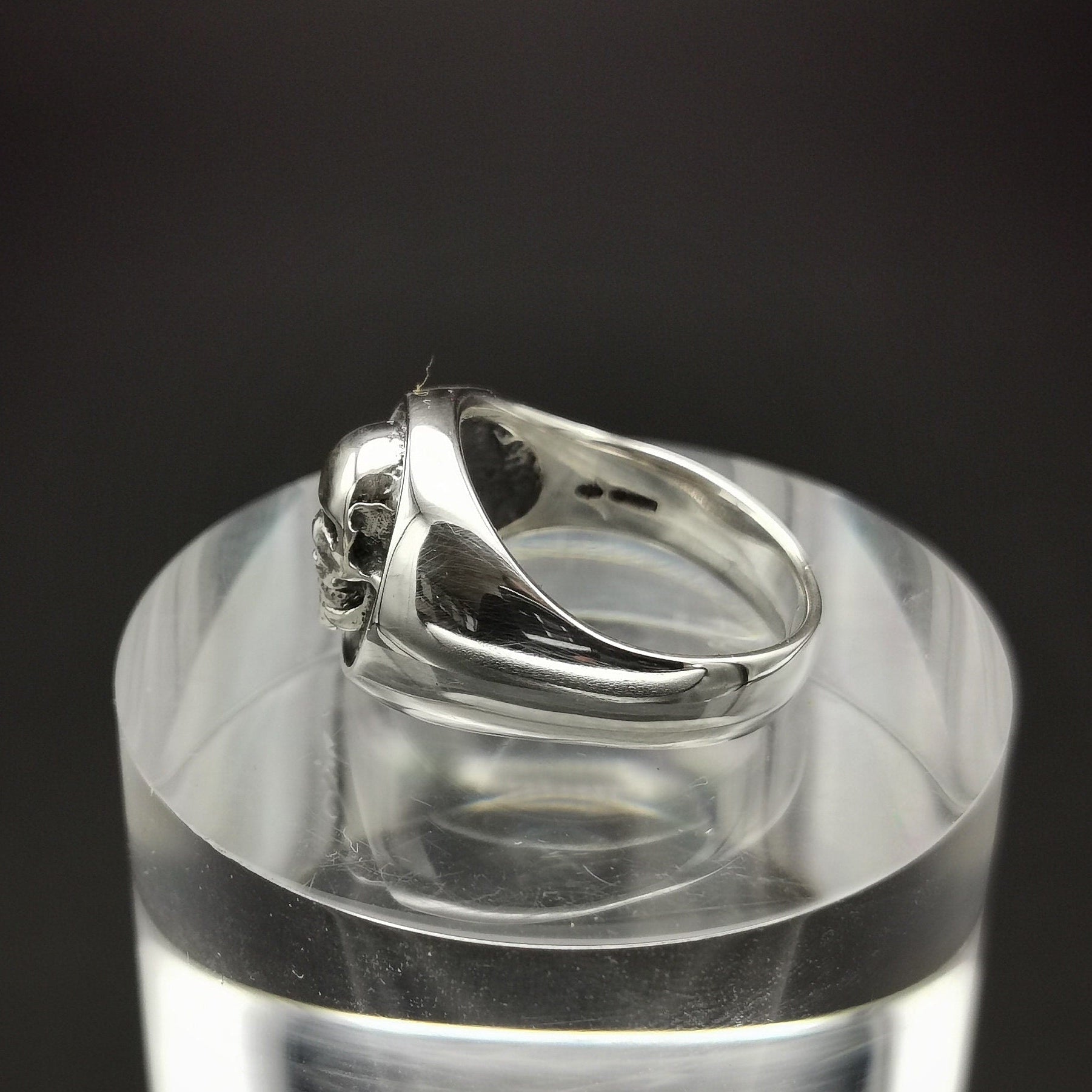 Silver ring on a clear stand with a black background